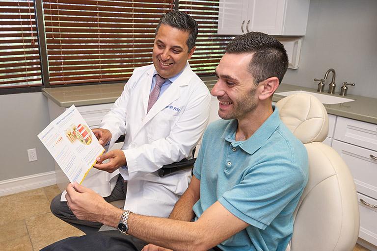 Dr. Alegre discussing gum disease with a patient as they look through a brochure.
