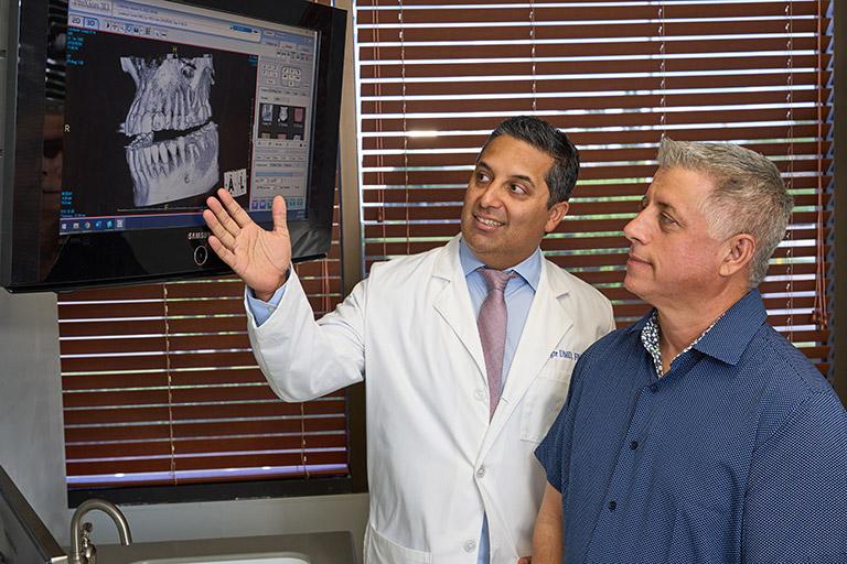 Dr. Alegre showing a patient an X-ray of their mouth.