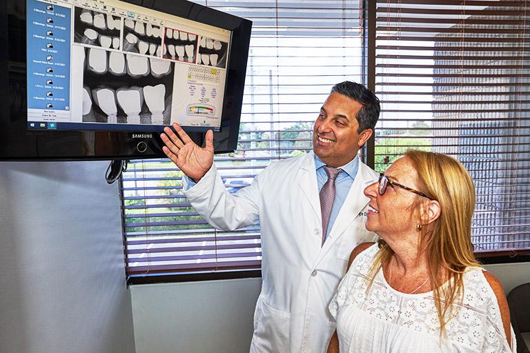 Dr. Alegre showing a patient dental images on a screen.